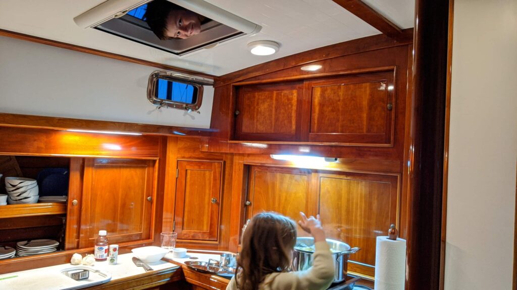 Julia throws clams into the pot for a low country boil, while James observes from the hatch at nightfall, in River Dunes, NC